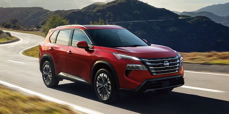 Red 2024 Nissan Rogue driving on mountainous road